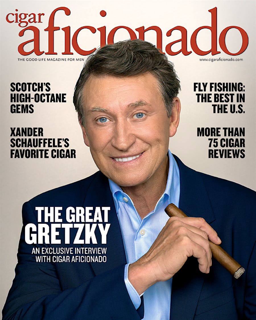 Cigar Aficionado magazine cover featuring a man holding a cigar with text about the magazine's content.