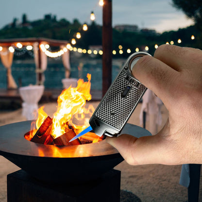 Hand using a lighter to ignite wood in a fire pit with a scenic background